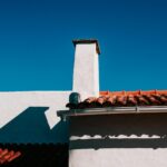 Low angle view of a traditional terracotta rooftop under a clear blue sky in summer.