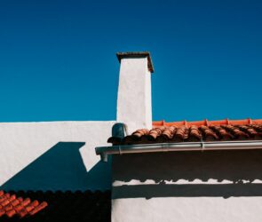 Low angle view of a traditional terracotta rooftop under a clear blue sky in summer.